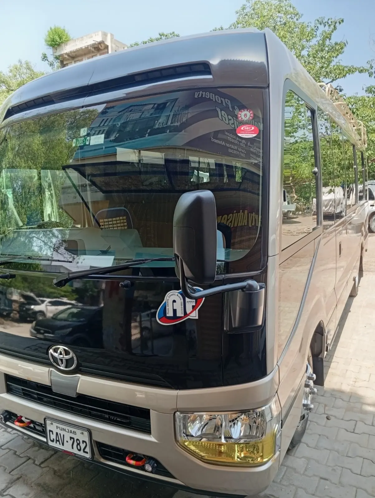 Front of a champagne-coloured Toyota Coaster with the Amber Tours emblem