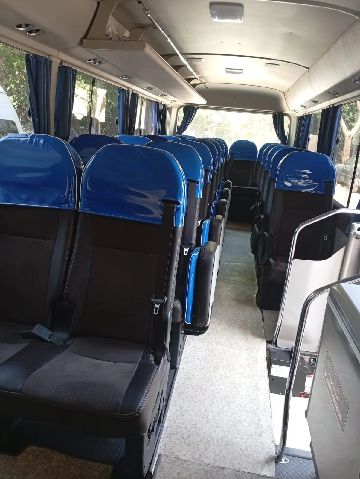 Inside a Toyota Coaster: rows of blue reclining seats with seat belts